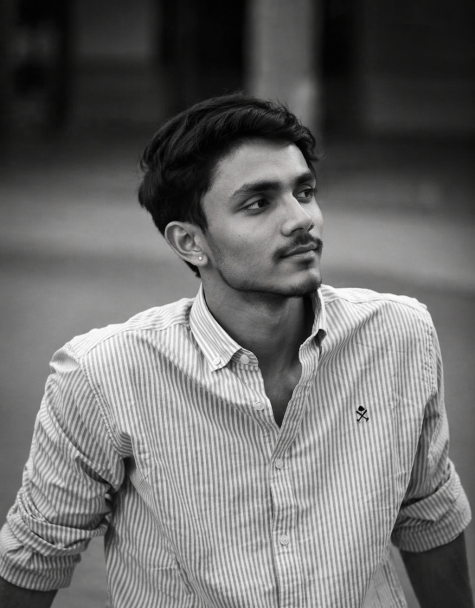Black-and-white portrait of a young man in a striped shirt looking sideways with a calm expression and blurred background.